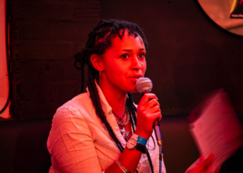 Gabriel Leavey under red lighting speaking into a microphone